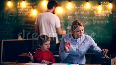 这个男孩和老师在教室里画画。 学习观念。 穿制服的学童。 教室里的老师。